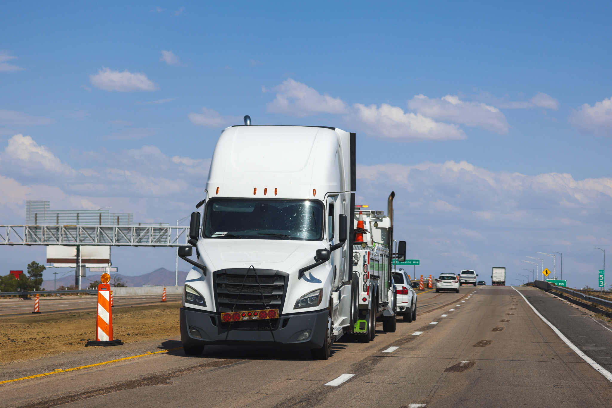 White heavy duty tow truck hauling a commercial vehicle to prevent transmission damage